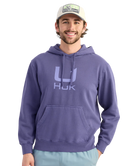 Man wearing a BLUE purple hoodie with a logo, standing against a white background