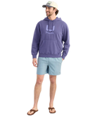 Man wearing a BLUE purple hoodie with a HUK logo, standing against a white background