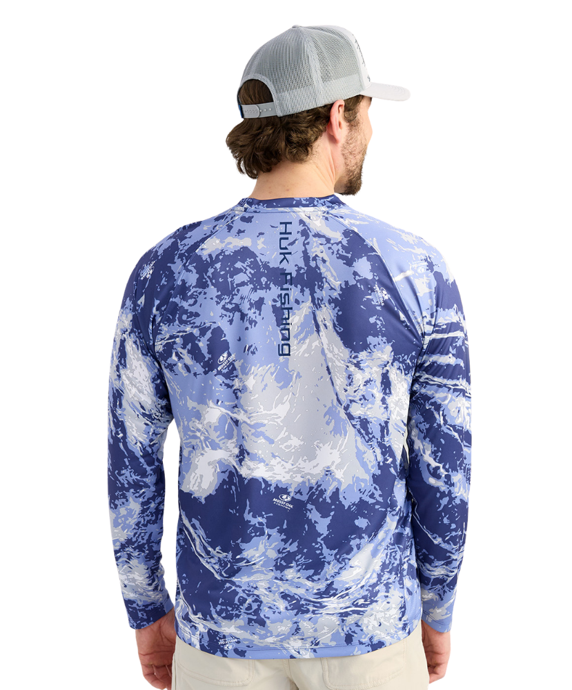 Man wearing a blue camouflage long-sleeve shirt with 'Huk' branding on the back.