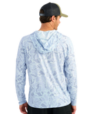 Man wearing a light blue camouflage hoodie with 'Huk' logo and a green cap on a white background