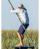 Man wearing a light blue camouflage hoodie with 'Huk' logo and a green cap on a white background