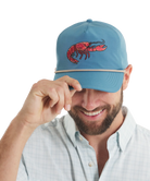 Man wearing a blue cap with a red CRAWFISH design on a white background