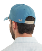 Man wearing a blue cap with a logo on the back against a white background