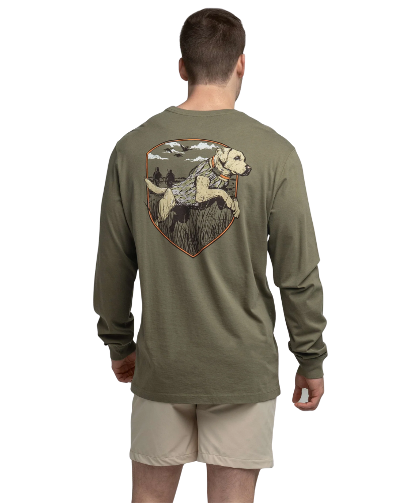 Man wearing an olive green long-sleeve shirt with a graphic of a dog and nature on the back, standing against a white background.