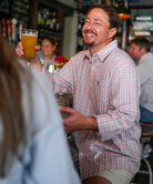 Man in a dress shirt holding a glass of beer in a bar setting