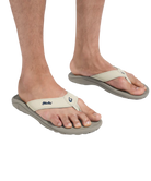 Beige flip-flops worn on feet with a white background
