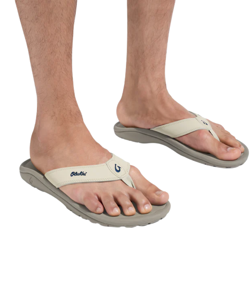 Beige flip-flops worn on feet with a white background