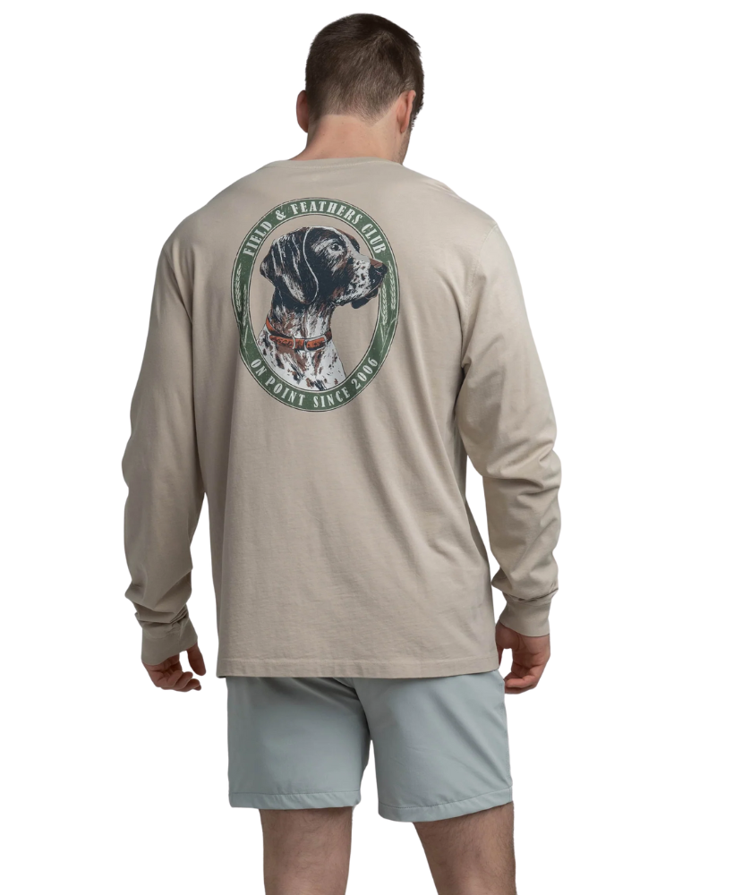 Man wearing a beige long-sleeve shirt with a GSP dog graphic on the back, standing against a white background.