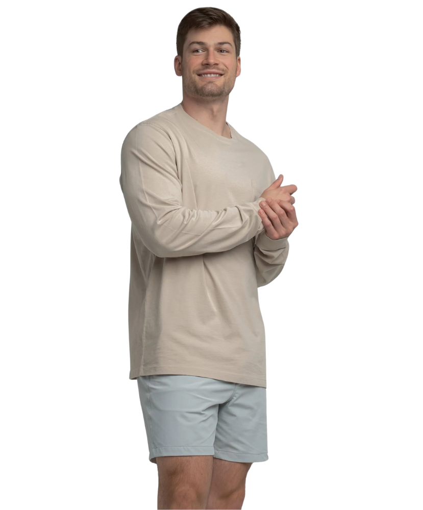 Man wearing a beige long-sleeve shirt and light gray shorts on a white background