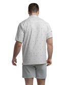 Man wearing a white polo shirt with red Alabama state outline pattern and 'SSCO' logo on a white background and light shorts on a white background