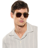 Man wearing Krewe sunglasses and a light gray shirt on a white background