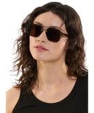 Woman wearing dark sunglasses with a plain background