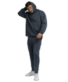 Man wearing a blue hoodie and pants with white sneakers on a white background