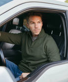 Man wearing a green pullover with a quarter zip on a white background