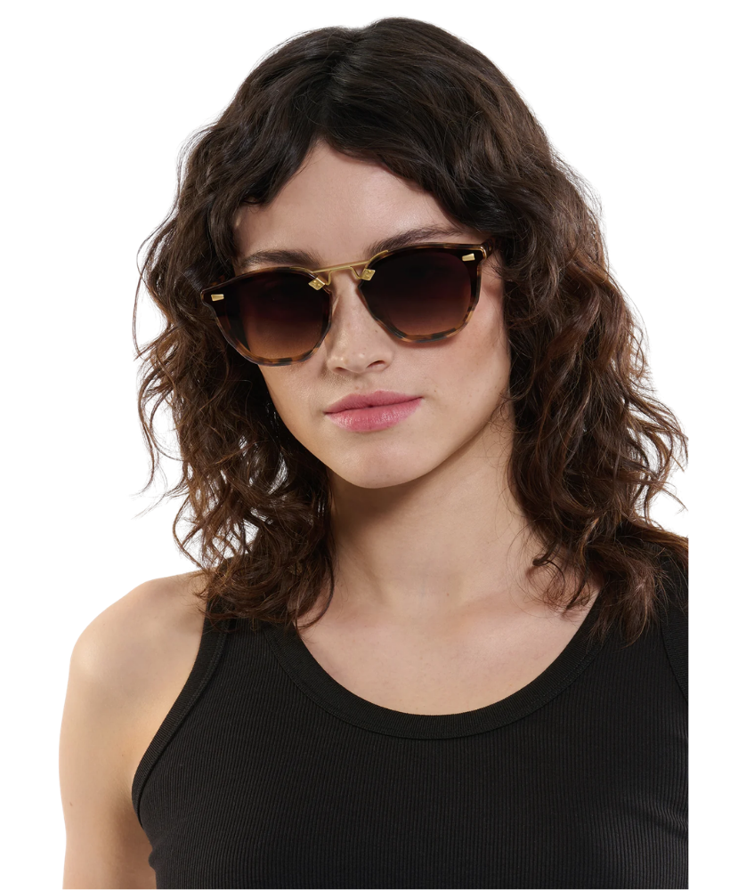 Woman wearing Krewe sunglasses with a neutral background