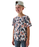 Child wearing a camo patterned t-shirt and cap on a white background