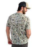 Man wearing a camouflage t-shirt with 'HUK Performance' logo on the back, standing against a white background.