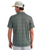 Man wearing a patterned polo shirt and cap on a white background