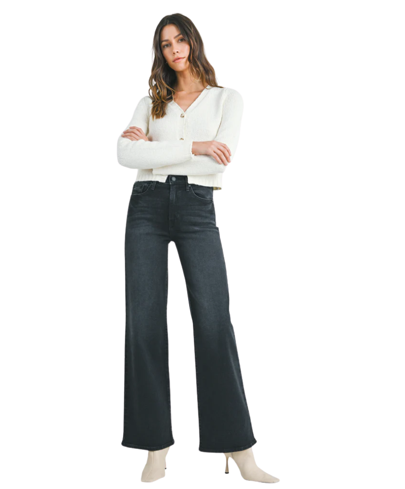 Woman wearring washed black denim pants with a high rise and wide leg