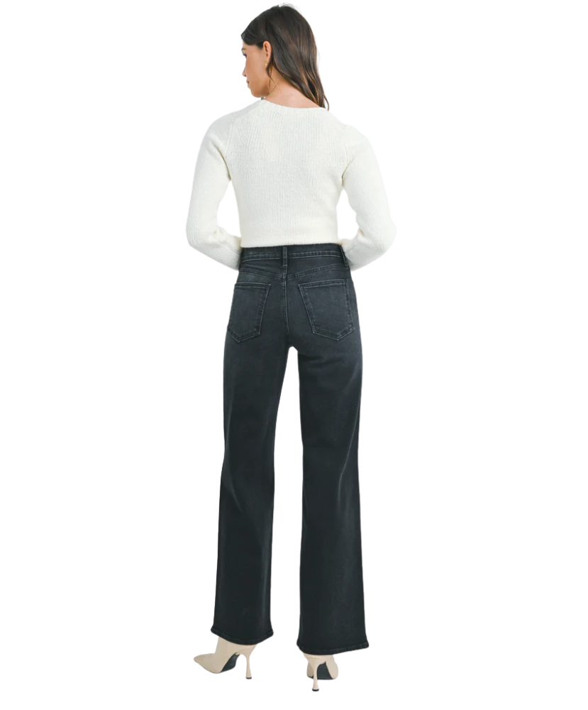 Woman wearring washed black denim pants with a high rise and wide leg