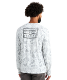 Man wearing a white camouflage long-sleeve shirt with 'Huk Performance Fishing' logo on the back.