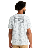 Man wearing a white camouflage t-shirt with 'Huk Performance Fishing' logo on the back.