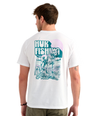 Man wearing a white Huk Fishing t-shirt with a graphic of a dog on the back.