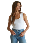 Woman wearing a white tank top and blue jeans on a white background