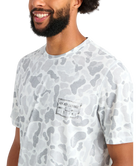 Man wearing a white camouflage t-shirt with a brand logo on a white background