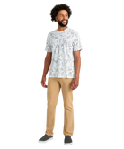 Man wearing a white patterned t-shirt and beige pants on a white background
