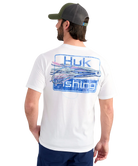 Man wearing a white Huk Fishing t-shirt with a fishing lure graphic on the back, standing against a white background.