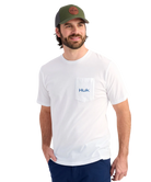 Man wearing a white Huk shirt and green cap on a white background