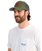 Man wearing a green and gray cap and white Huk shirt on a white background