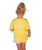 Child wearing a yellow shirt with 'SHADES' branding on a white background