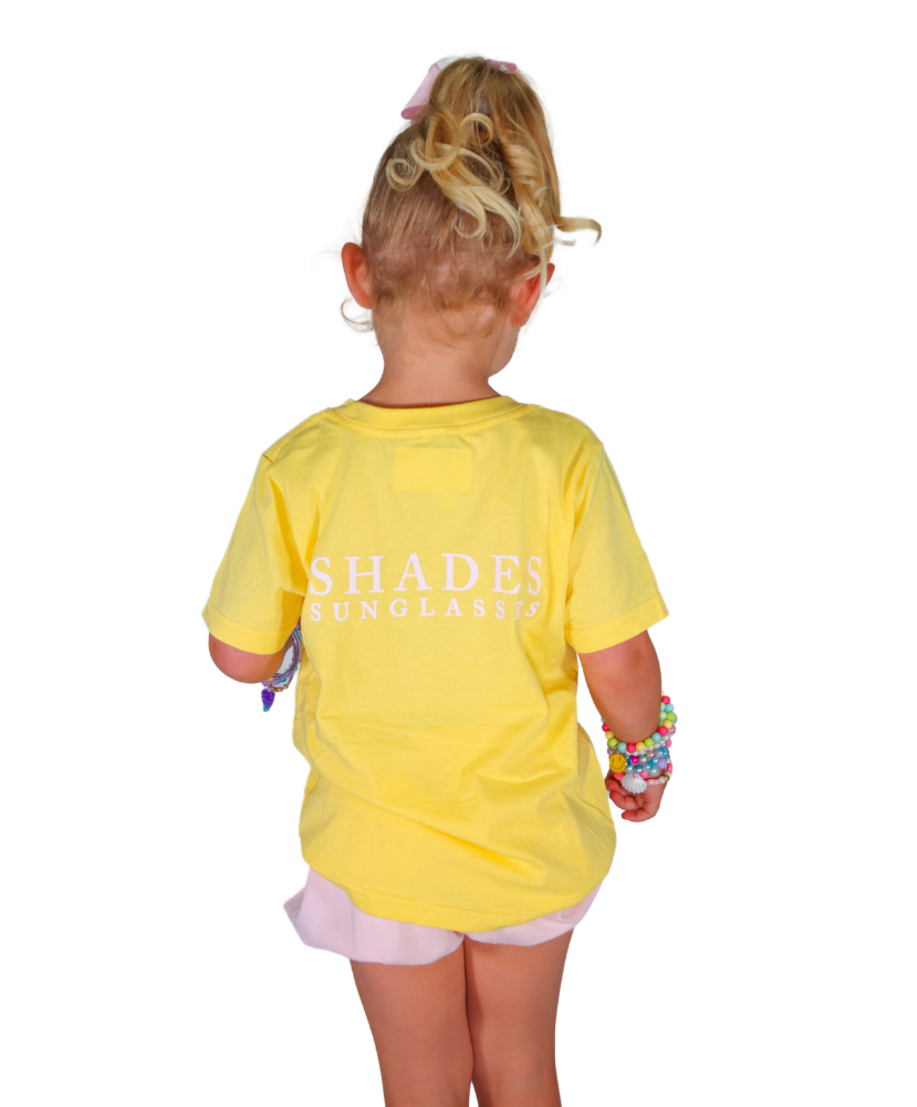Child wearing a yellow shirt with 'SHADES' branding on a white background