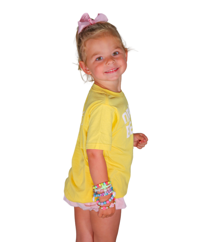 Young girl wearing a yellow outfit with a white logo on a white background