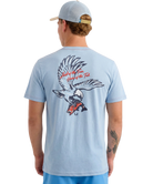 Man wearing a light blue HUK t-shirt with an eagle design on the back, standing against a white background.
