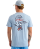 Man wearing a light blue HUK t-shirt with an eagle design on the back, standing against a white background.