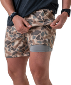 Person wearing camouflage athletic shorts with a gray liner on a white background