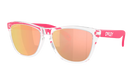 Oakley Frogskin Wayfarer-style sunglasses with a clear transparent frame, bright pink arms and bridge, and mirrored rose-gold lenses, shown on a plain white background.