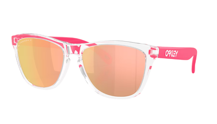 Oakley Frogskin Wayfarer-style sunglasses with a clear transparent frame, bright pink arms and bridge, and mirrored rose-gold lenses, shown on a plain white background.