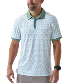 Man wearing a white duck and waterfowl patterned polo shirt with green accents on a white background