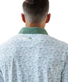 Man wearing a white duck and waterfowl patterned polo shirt with green accents on a white background