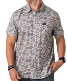 Person wearing a camouflage-patterned button-down shirt with a visible brand logo on a white background