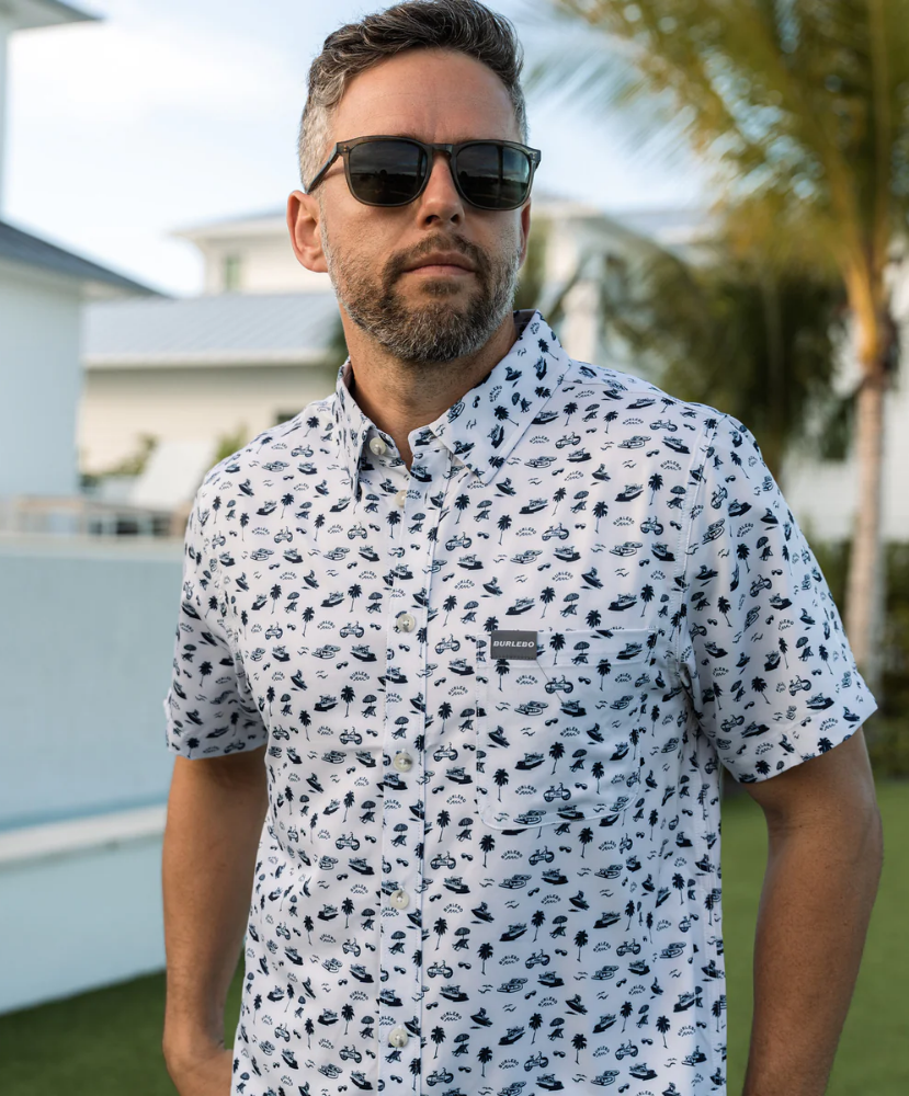 Man wearing a white short-sleeve button down shirt with a blue coastal pattern on a white background