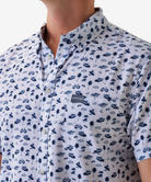 Man wearing a white short-sleeve button down shirt with a blue coastal pattern on a white background