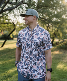 Man wearing a vintage camo patterned short-sleeve button down shirt on a white background