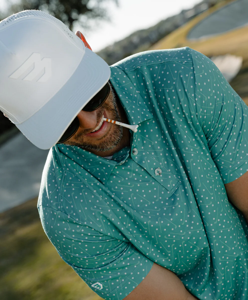 Man wearing a teal golf club and golf ball  dot polo shirt on a white background