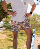 Person wearing camouflage swim shorts on a white background