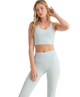 Woman wearing a light gray sports bra and leggings set on a white background